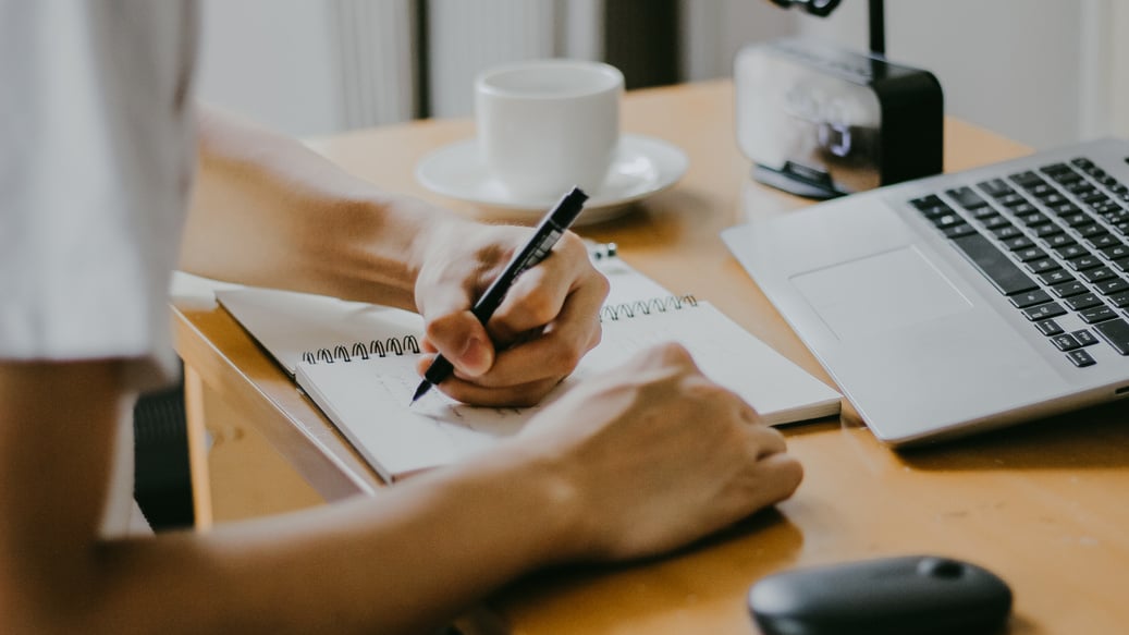 Student Writing on Notebook During Online Class